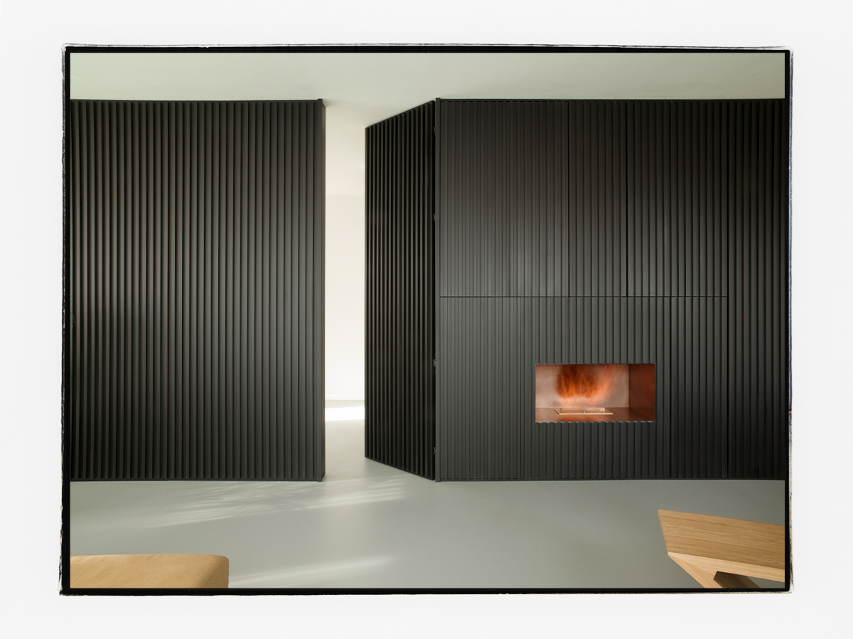 Raumhoher Raumteiler in schwarz mit integriertem Kamin und Stauraum